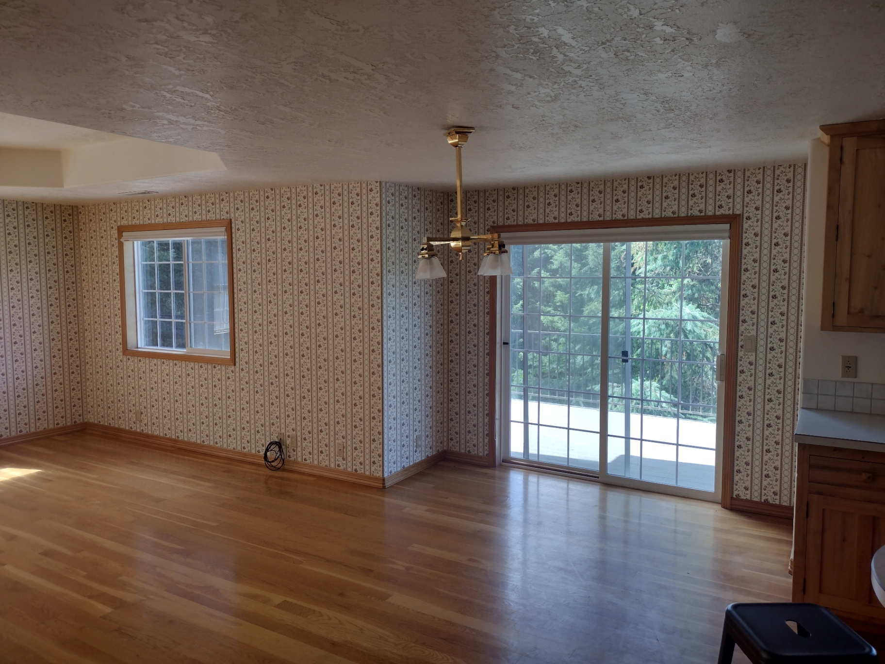 Spacious living and dining room with newly installed light hardwood floors and a sliding glass door